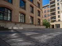 a brick courtyard has steps leading up to it, and a blue umbrella is on the ground