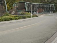 two large buildings on the side of the road with bushes in front of them and a person walking down the sidewalk