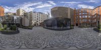 a wide angle fisheye photograph of modern buildings in an urban area with cobblestones