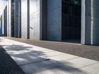 a sidewalk is lined with gray stone slabs and black windows of a high rise building