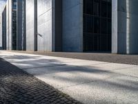 a sidewalk is lined with gray stone slabs and black windows of a high rise building