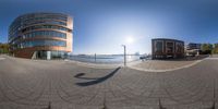 two street views of a city building and river in the background, and a sidewalk is lined with pavers to the left