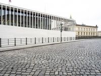 a cobblestone road near an empty building on the shore line of a river