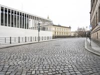 a cobblestone road near an empty building on the shore line of a river