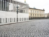 a cobblestone road near an empty building on the shore line of a river