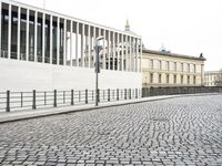 a cobblestone road near an empty building on the shore line of a river