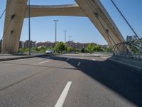 a truck driving across a bridge near a street corner near buildings and a bridge with many cables