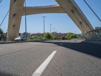 a truck driving across a bridge near a street corner near buildings and a bridge with many cables