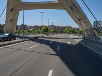 a truck driving across a bridge near a street corner near buildings and a bridge with many cables