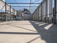 a hallway with a steel roof and many metal columns leading up into the building, on a sunny day