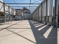 a hallway with a steel roof and many metal columns leading up into the building, on a sunny day