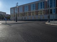 a street light next to an empty road in front of a building with a traffic light on top of it