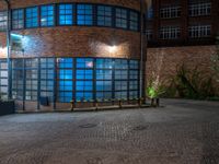 some dark blue windows in an industrial building with no one on the street to the right