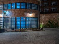 some dark blue windows in an industrial building with no one on the street to the right