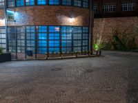 some dark blue windows in an industrial building with no one on the street to the right