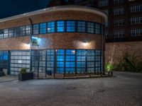 some dark blue windows in an industrial building with no one on the street to the right