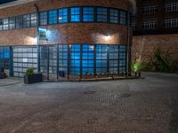 some dark blue windows in an industrial building with no one on the street to the right