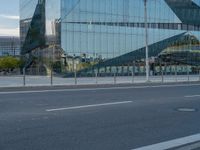 a large building with some glass on it's side near the road near a city