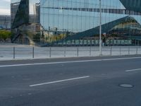 a large building with some glass on it's side near the road near a city