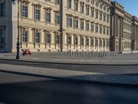 a street light next to an empty road in front of a building with a traffic light on top of it