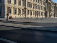 a street light next to an empty road in front of a building with a traffic light on top of it