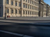 a street light next to an empty road in front of a building with a traffic light on top of it