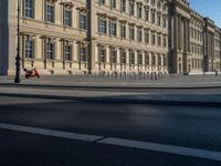 a street light next to an empty road in front of a building with a traffic light on top of it