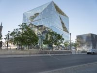 a car driving past a tall glass office building in the middle of a city area