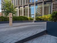 the side walk of a glass office building with concrete bricks and landscaping on each floor