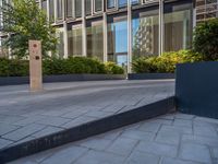 the side walk of a glass office building with concrete bricks and landscaping on each floor