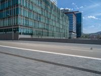 a very large office building near the road on a sunny day with people walking by