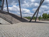 a person on a bike walking through a stone building entrance, in front of an enormous glass wall and stairs