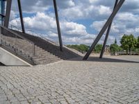 a person on a bike walking through a stone building entrance, in front of an enormous glass wall and stairs