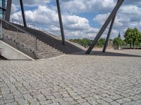 a person on a bike walking through a stone building entrance, in front of an enormous glass wall and stairs