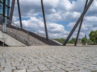 a person on a bike walking through a stone building entrance, in front of an enormous glass wall and stairs