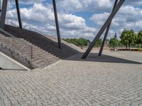 a person on a bike walking through a stone building entrance, in front of an enormous glass wall and stairs