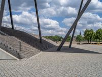 a person on a bike walking through a stone building entrance, in front of an enormous glass wall and stairs