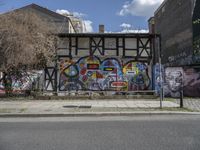 the street in front of the graffiti covered building is empty and empty, but has two rows