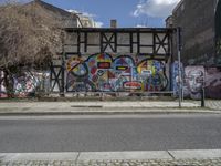 the street in front of the graffiti covered building is empty and empty, but has two rows