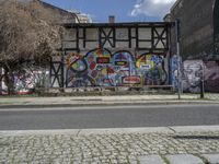 the street in front of the graffiti covered building is empty and empty, but has two rows