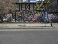 the street in front of the graffiti covered building is empty and empty, but has two rows