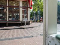 an open doorway shows a small sidewalk outside of a store with some shops in the window