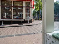 an open doorway shows a small sidewalk outside of a store with some shops in the window