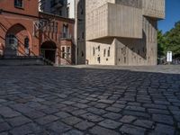 cobblestone driveway surrounded by modern buildings on sunny day with sun reflecting onto the windows