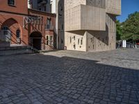 cobblestone driveway surrounded by modern buildings on sunny day with sun reflecting onto the windows