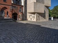 cobblestone driveway surrounded by modern buildings on sunny day with sun reflecting onto the windows