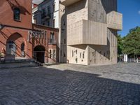 cobblestone driveway surrounded by modern buildings on sunny day with sun reflecting onto the windows