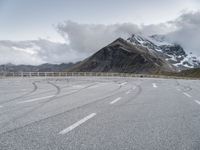 the road has two winding lines and snow covered mountains in the background of the photo