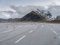 the road has two winding lines and snow covered mountains in the background of the photo