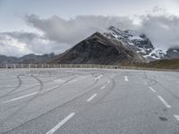 the road has two winding lines and snow covered mountains in the background of the photo